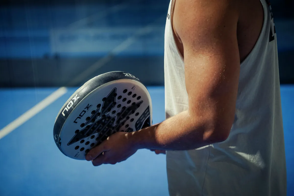 Spieler mit Padel-Racket in der Hand auf dem blauen Court im Padelhouse